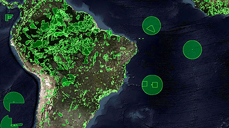 An aerial image of South America in brown, green, and blue, with areas highlighted in neon green